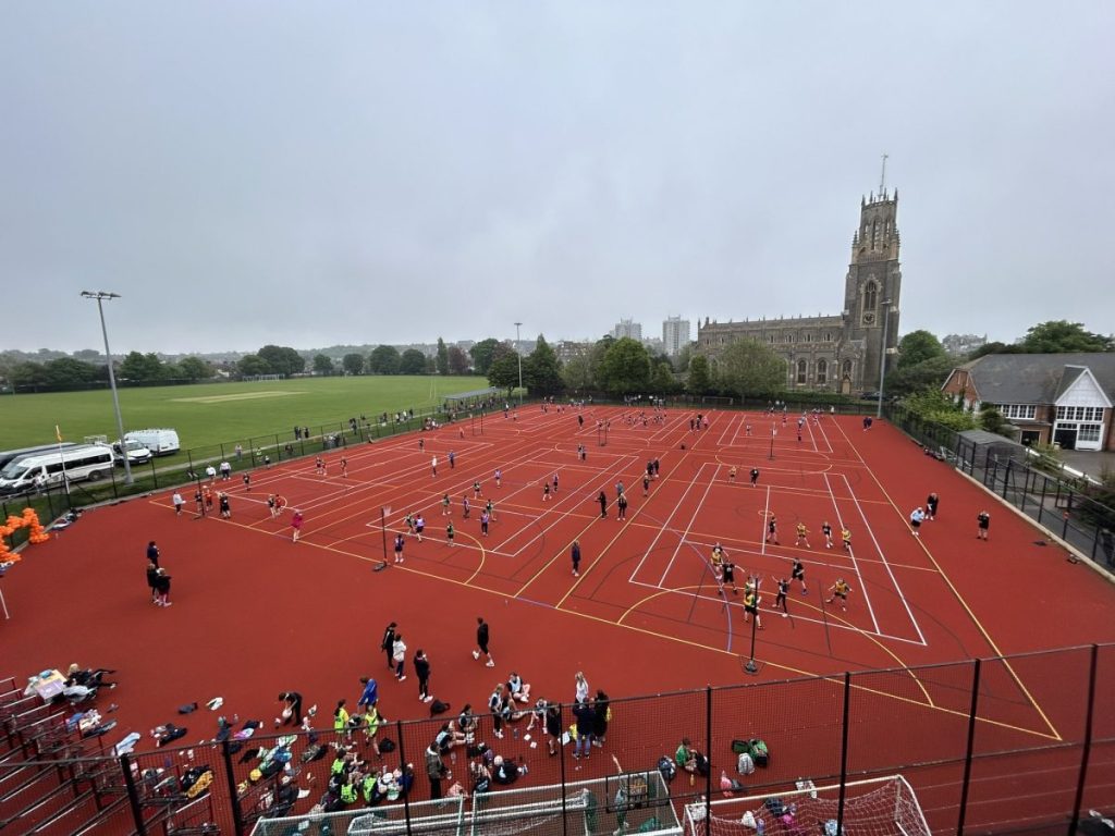 MUGA at Chatham used for Netball & Multi-Sports. Orange court with a church in the background.